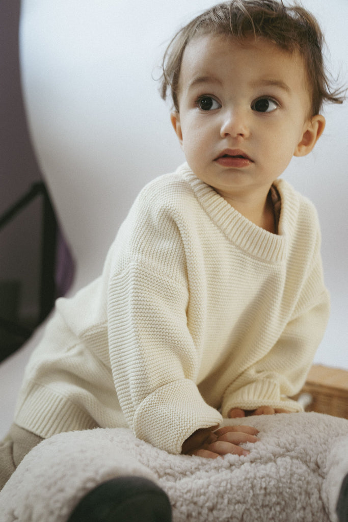 Kind mit großen Augen trägt einen feinen Strickpullover aus Bio-Baumwolle