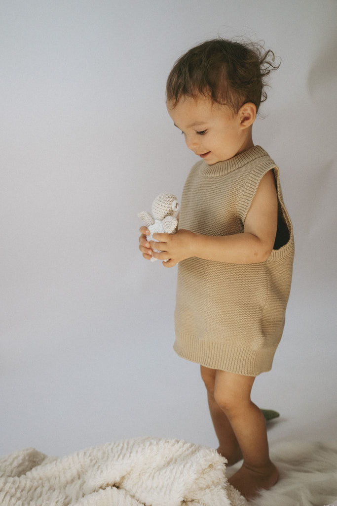 Kind mit einem schicken Pullunder in Beige aus feiner Bio-Baumwolle in der Hand hält es eine Schildkröte aus Strick
